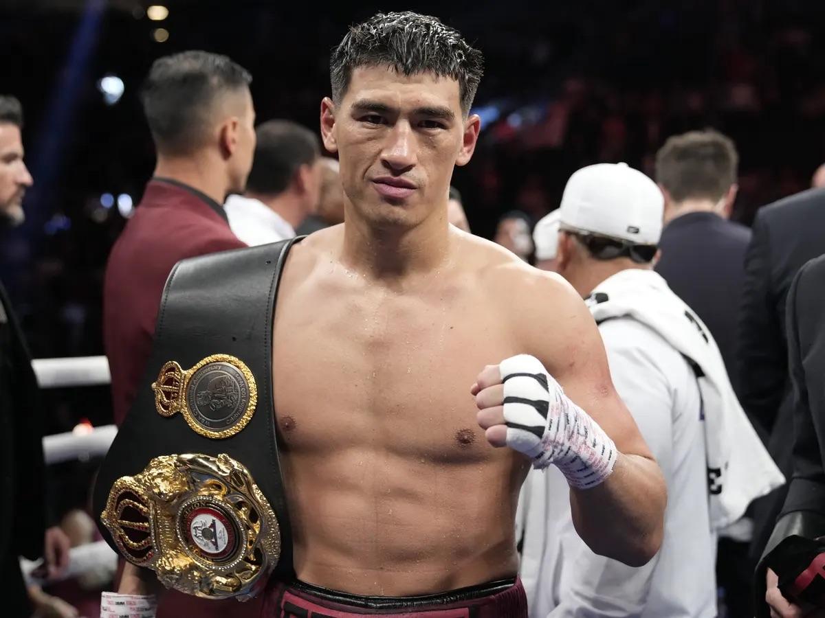 Dmitry Bivol (à droite, gants argentés Rival) portant un direct du gauche précis sur le visage d'un adversaire portant un short estampillé BETERBIEV lors d'un combat de boxe mi-lourds — illustration de la domination technique de Bivol pendant sa défense de ceinture WBA